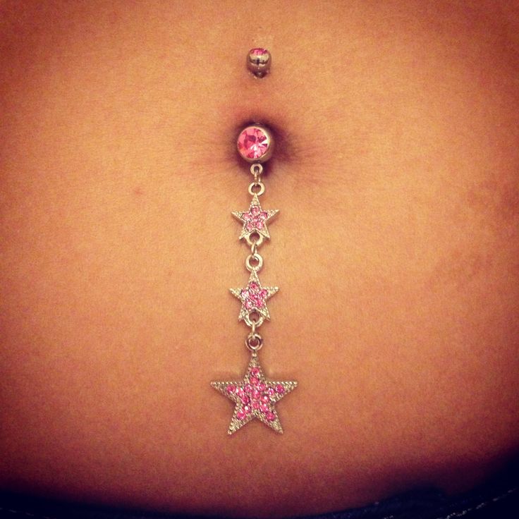 a woman's belly with pink and white stars attached to the navel ring