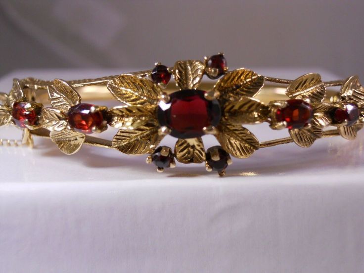 Please look at the measurements listed below as closeup photo's can make the items appear larger   gorgeous vintage estate heavy ( 18.58 grams approximately - we consider this a heavier & wider style bracelet yet please judge for yourself by the weight listed ) & wide ( 5/8" inches - 16.3mm wide at its widest points ) 14k 14k karat yellow gold nine (9) genuine natural real oval & round cut red rhodolite garnet gemstones clusters ornate floral flower rose scroll leaf feather textured gold designs tiered wrap around art deco victorian designer style opening tennis bangle bracelet  this is a gorgeous and stunning  bracelet    this gorgeous bracelet opens for easy access to put on or take off  a very well made bracelet with a good working order inserting clasp and extra outside security chain Antique Red Bracelet For Formal Occasions, Red Antique Bracelet For Formal Occasions, Red Vintage Bangle For Wedding, Vintage Red Bracelet For Wedding, Vintage Red Bracelets For Wedding, Vintage Red Bracelets For Anniversary, Vintage Red Wedding Bracelet, Feather Texture, Rose Leaf