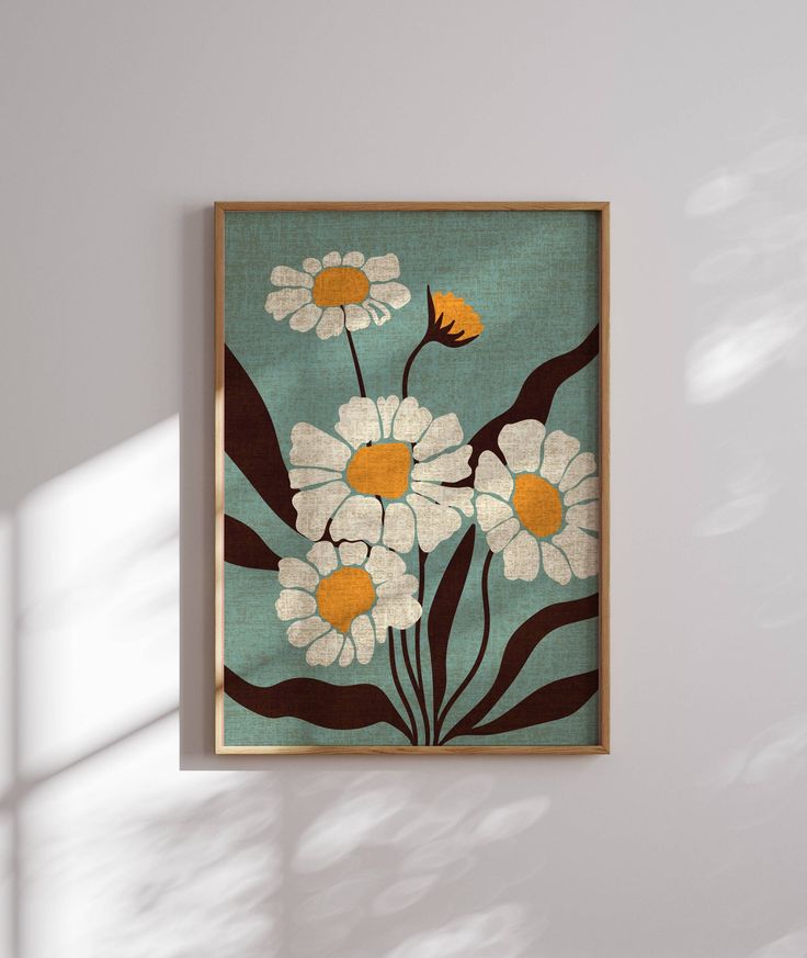 a painting hanging on the wall with white and yellow daisies in front of it