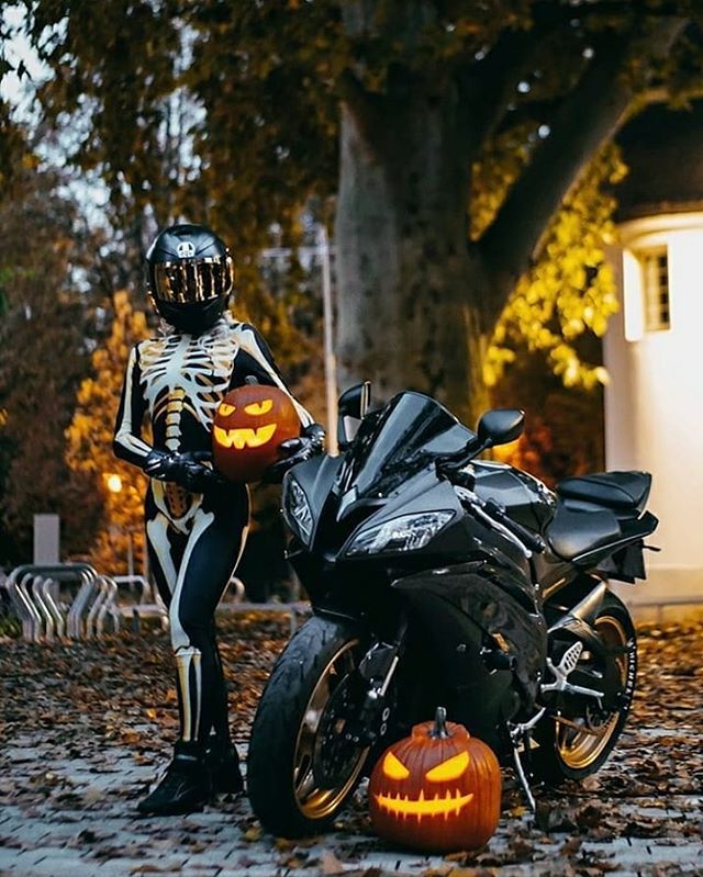 a person dressed as a skeleton sitting on a motorcycle with jack - o'- lanterns