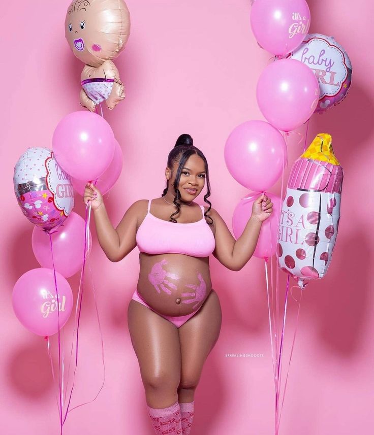 a pregnant woman posing for a photo with balloons