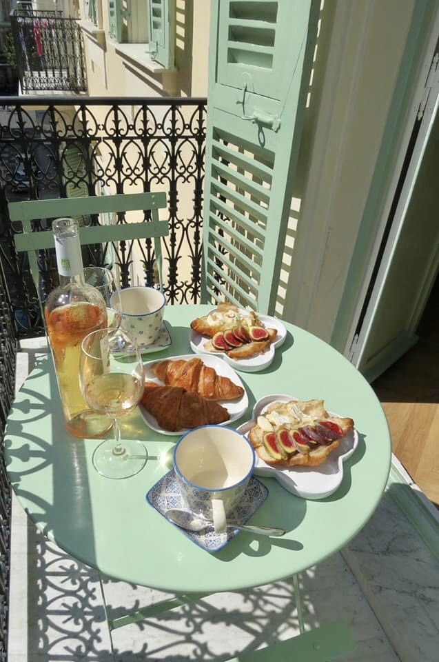 a table that has food on it and drinks in front of the window with shutters