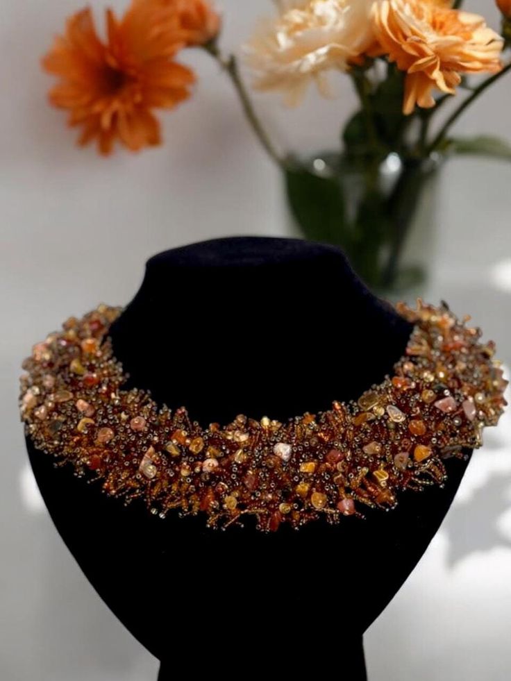 This stunning handmade necklace features an intricate design adorned with an array of delicate beads and natural stones in rich brown and amber tones. The wide band showcases a mix of earthy hues, giving it a luxurious and textured look. Natural stones in this necklace are known for their grounding energy, promoting stability and inner strength. Perfect for adding a touch of elegance and positive energy to any outfit, this necklace is both stylish and meaningful. Features: Handmade with high-quality beads and natural stones Intricate beaded design in shades of brown and amber Wide band for a bold and fashionable statement Natural stones represents stability, inner strength, and grounding energy Perfect accessory for special occasions or everyday wear Makes a thoughtful gift for a loved one Brown Multi-strand Jewelry For Party, Brown Multi-strand Party Jewelry, Handmade Amber Multi-strand Necklace, Luxury Brown Jewelry With Natural Stones, Unique Brown Beaded Necklace With Polished Beads, Brown Faceted Beads Jewelry For Party, Elegant Brown Multi-strand Beaded Necklaces, Luxury Handmade Beaded Necklace As Gift, Luxury Handmade Beaded Necklace For Gift