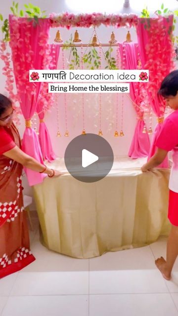 two women standing next to each other near a table with pink curtains and decorations on it