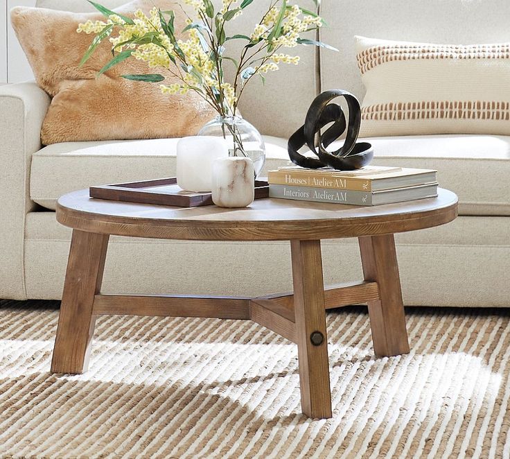 a living room with a couch, coffee table and flowers on the end table in front of it