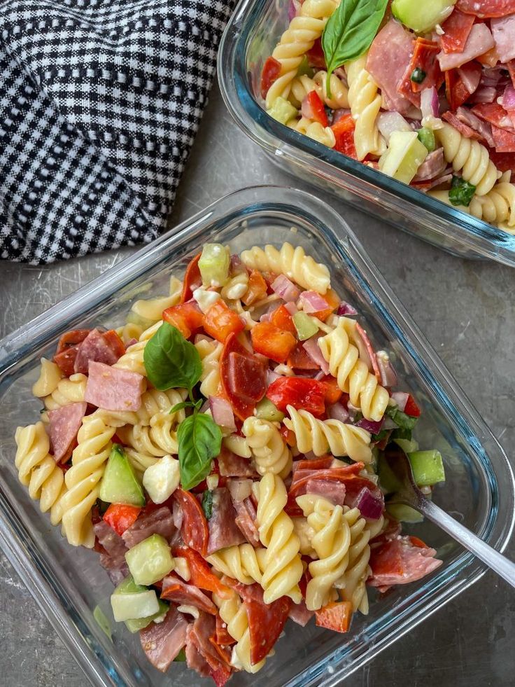 two glass dishes filled with pasta salad on top of a table