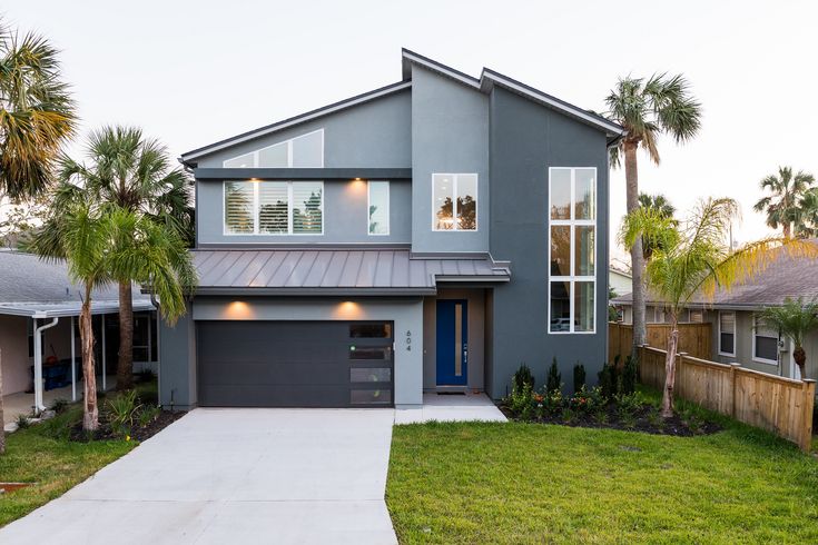 a gray house with palm trees in the front yard