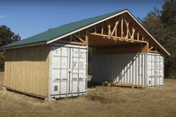 an outhouse made from shipping containers sits in the middle of a field