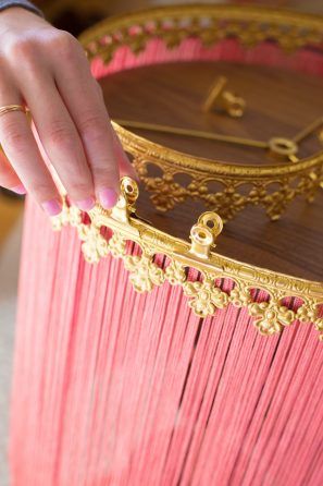 a person holding onto a pink table with gold trimmings on it and a clock in the background