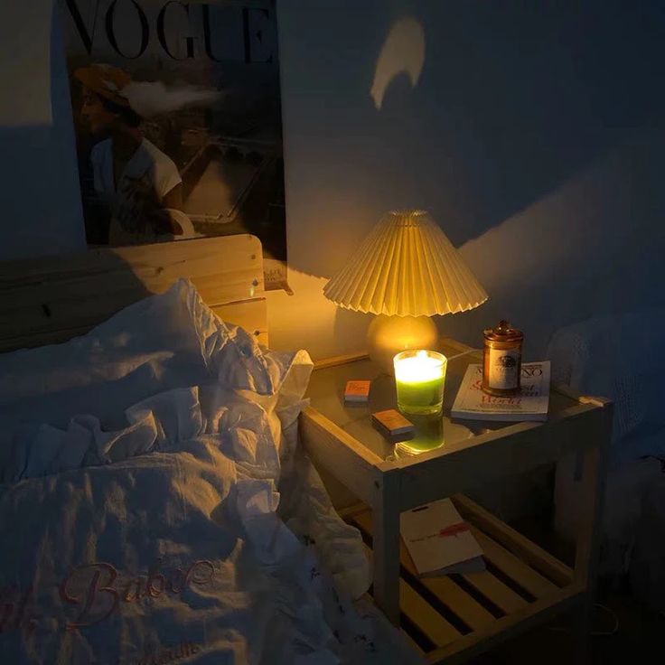 a table with a lamp on it next to a bed