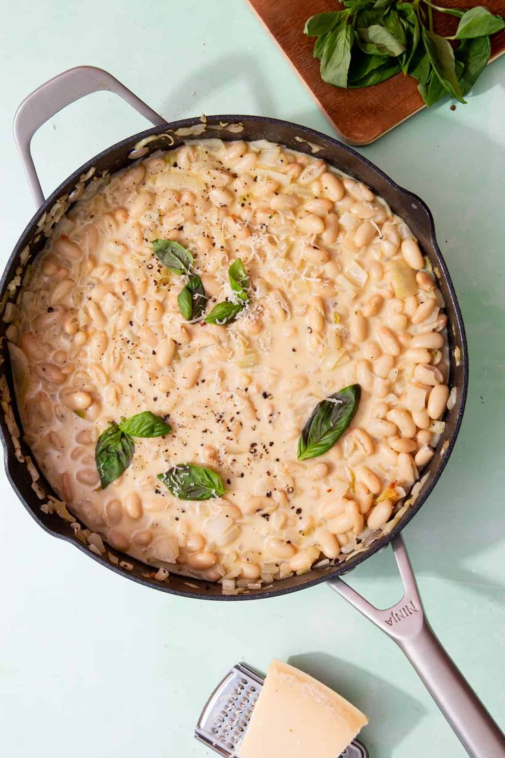 macaroni and cheese in a skillet on a blue surface with basil leaves