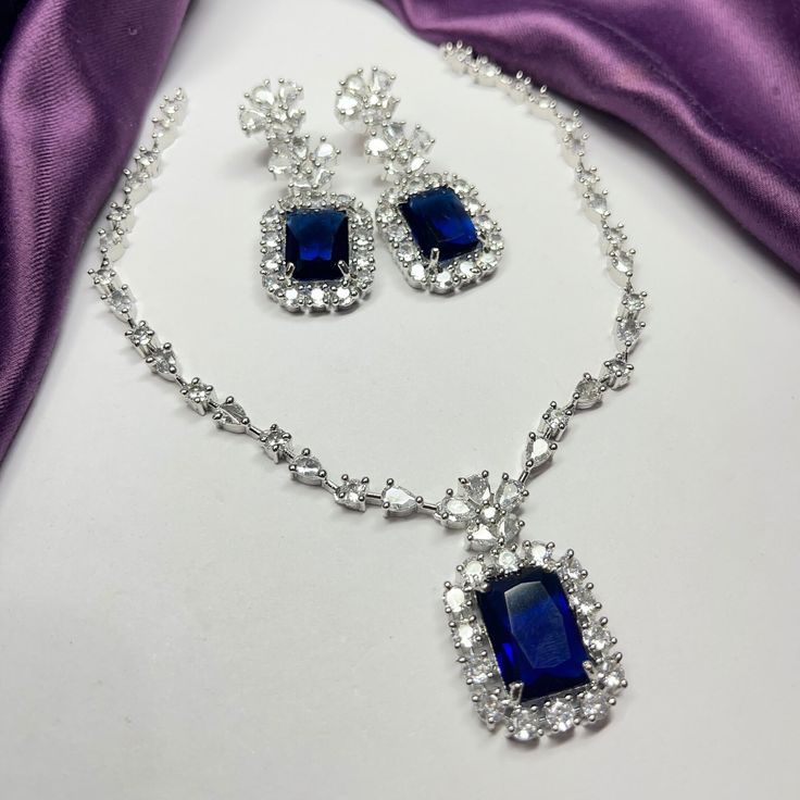 Gorgeous fine quality lab blue sapphire  and  CZ diamonds studded necklace with white gold rhodium plating and matching Earrings Item contains: Necklace and earrings AAA quality cubic zirconia used. Highest quality and craftsmanship Necklace Fitting is adjustable Earrings Closure: Pushback Necklace Closure: chain with Hook Details-  -Handmade item -Delivery from a small business in India -Materials: white rhodium, stones, cz, zircon, American diamond -Jewellery type: Earrings, Necklace *CARE INSTRUCTION* You can use Jewelry for years together with the help of below jewelry care instructions. * Protect from sharp blows/scratches and extreme temperature. * Avoid contact with perfumes, sprays, chemicals and water. * Keep in a clean, dry and airtight Zip-pouch. * Wipe it using a soft cloth aft Sapphire Jewelry With Sparkling Stones For Wedding, Luxury American Diamond Jewelry Sets For Party, Exquisite Diamond Accented Jewelry For Parties, Exquisite Diamond-accented Jewelry For Party, Dazzling Party Jewelry Sets With Diamond Accents, Luxury Cubic Zirconia Bridal Necklace For Party, Exquisite Party Jewelry With Diamond Accents, Elegant Sapphire Jewelry With Hand Set, Elegant Sapphire Jewelry For Party