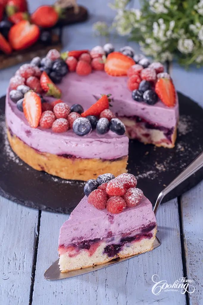 a cake with berries and powdered sugar is on a black platter next to a knife