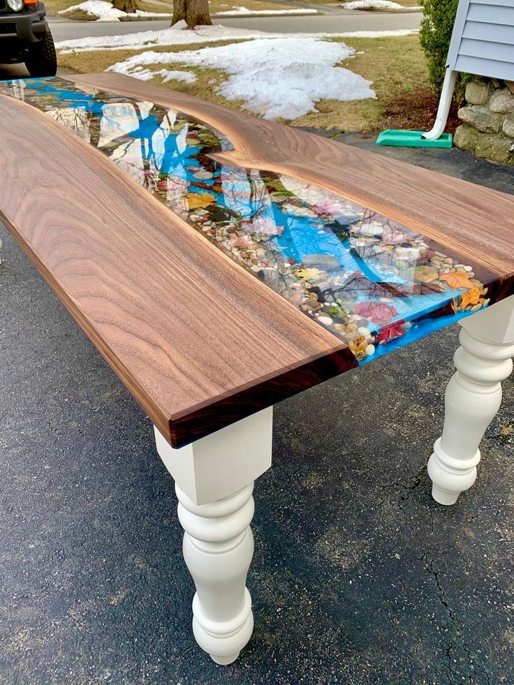 a wooden table that has been painted with different colors and designs on it, sitting in front of a house