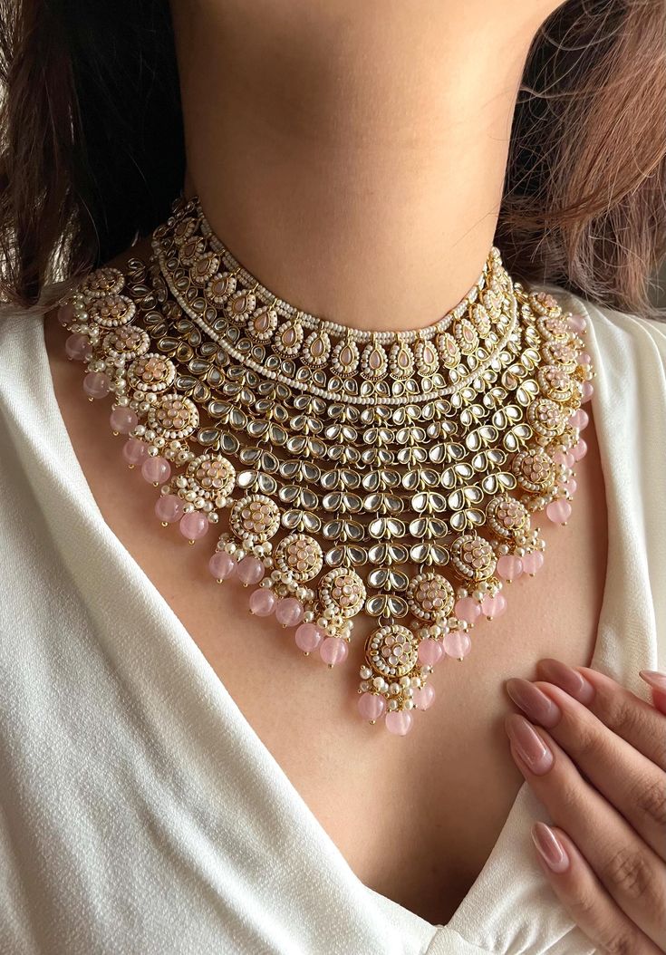 Adorn yourself in timeless elegance with this exquisite pink Kundan and zircon necklace set, perfect for weddings and special occasions. Crafted with meticulous attention to detail, the set features delicate pink hues reminiscent of Pakistani and Punjabi traditions, with a touch of Bollywood glamour. Complete with matching earrings and a stunning maangtika, this Indian Kundan ensemble effortlessly captures the essence of sophistication and grace. Measurements:   Necklace Length-14" Necklace Width- 9" Centre piece length -4" Earring Length-3" Earrings width-1.5" Each earring weighs: 28gms  Maangtika Length- 7" Maangtika Width- 1.5" Pakistani Jewelry Sets, Latest Bridal Jewellery Designs, Punjabi Jewellery, Light Pink Bridesmaids, Kundan Choker Necklace, Bollywood Glamour, Gold Necklace For Men, Pakistani Earrings, Bridal Jewelry Sets Brides