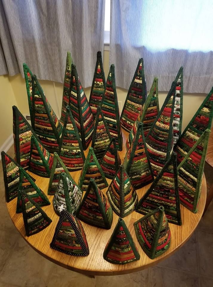 there are many small christmas trees made out of fabric on the table in front of the window