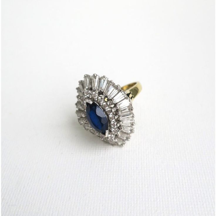 This is part of Chairish’s Costume Jewelry assortment.  An impressive vintage designer cocktail ring attributed to Benedetto Panetta, circa mid-20th century, 1960s. This cocktail ring is comprised of faux-diamonds and a single marque blue faux-sapphire, all set in sterling silver with gold wash on the rings' shank/band. The rings center marque stone is surrounded by round brilliant cut faux-diamonds and then tapered baguettes. The color of the center marque stone is a deep saturated blue hue, wi Oval Brilliant Cut Party Ring, Vintage Cluster Diamond Ring For Formal Occasions, Vintage Sapphire Ring With Diamond Accents For Formal Events, Evening Diamond Ring With 17 Jewels, Oval Diamond Ring For Party, Vintage Sapphire Ring With Diamonds For Formal Occasions, Vintage Cubic Zirconia Sapphire Ring For Anniversary, Vintage Marquise Diamond Ring, Elegant Multi-stone Party Rings