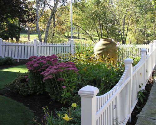 a white picket fence surrounded by flowers and trees