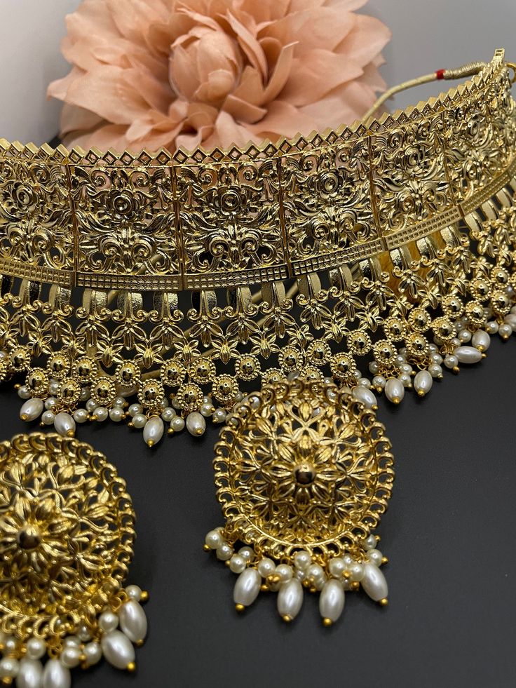 This is a beautiful antique gold choker set with matching earrings and comes with pearl details. It can be worn fir a statement look or complete bridal set as well. Elegant Kundan Necklace In Antique Gold, Elegant Antique Gold Kundan Necklace, Ceremonial Gold Pearl Bridal Necklace, Ornate Metal Jewelry For Wedding, Traditional Antique Gold Bridal Necklace For Wedding, Gold Sets With Intricate Design For Reception, Antique Gold Jewelry For Wedding, Elegant Heavy Bridal Accessories For Festive Season, Elegant Antique Gold Kundan Necklace With Intricate Design