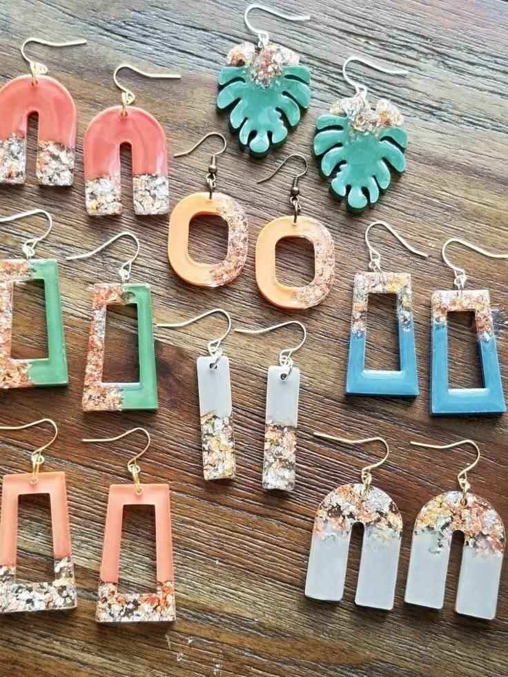 many different colored earrings on a table with one being made out of wood and the other is