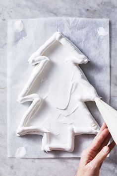 someone is decorating a christmas tree with white icing on a sheet of paper