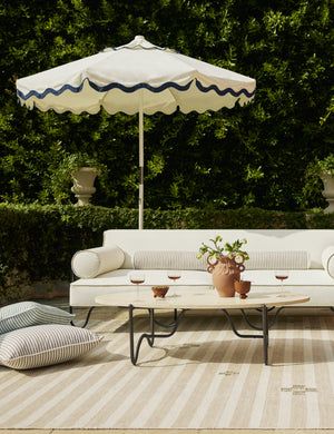 an outdoor seating area with umbrellas and potted plants on the floor, in front of trees