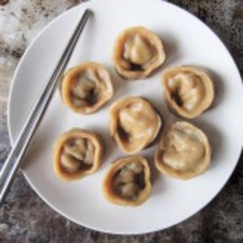 a white plate topped with dumplings and chopsticks