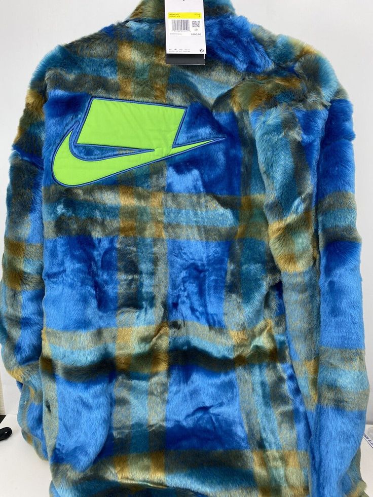 Stand out in style with this Nike Sportswear Essential faux fur jacket. The plaid pattern and multicolor design give it a trendy and unique look. The jacket features a button closure and embroidered logo accents that add a touch of elegance to this relaxed fit, long-length coat. Perfect for travel, casual wear, or any occasion, this jacket is made of high-quality faux fur fabric that provides warmth and comfort during the winter, fall, and spring seasons. It is an oversized jacket that perfectly Blue Sporty Outerwear With Relaxed Fit, Blue Sporty Relaxed Fit Outerwear, Sporty Blue Relaxed Fit Outerwear, Blue Oversized Sports Outerwear, Oversized Blue Sports Outerwear, Blue Oversized Outerwear For Sports, Oversized Blue Outerwear For Sports, Casual Fur Coat For Cold Weather, Nike Winter Outerwear With Relaxed Fit