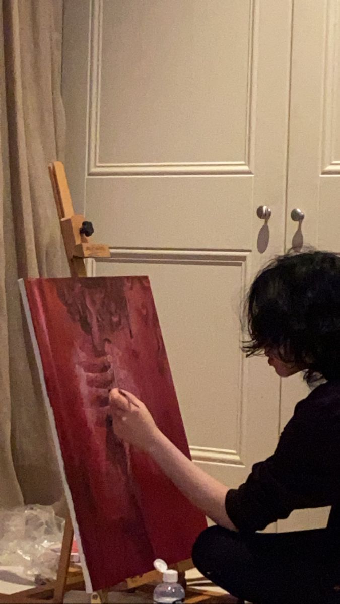 a woman is sitting on the floor painting