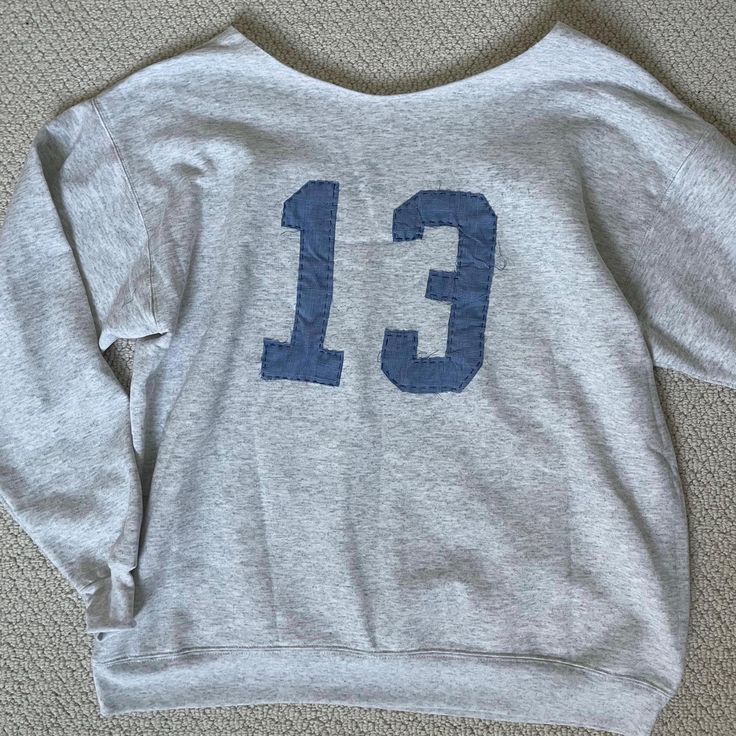 a sweatshirt with the number thirteen printed on it sitting on top of a carpeted floor