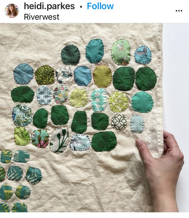 a person holding up a piece of cloth with different designs on it and the fabric is green