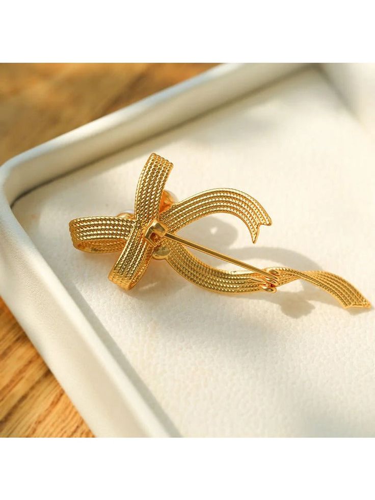 Our Bow Freshwater Pearl Brooch features a charming bow design. Meticulous craftsmanship and the use of high-quality materials create a polished and luxurious accessory that strikes the perfect balance between texture and comfort. Metal: 18K Recycled Gold Plated On Brass Gemstone:Freshwater Pearl Pearl Dimensions:7mm Dimensions:25*60mm Weight:8.5g Elegant Yellow Gold Brooches For Party, Elegant Yellow Gold Party Brooches, Chic Gold Brooch For Evening, Gift Bow Brooch, Elegant Anniversary Brooch With Bow, Elegant Brooches With Decorative Bow For Anniversary, Gold Wedding Brooches In Chic Style, Gold Wedding Brooches Chic Style, Elegant Anniversary Brooch With Decorative Bow