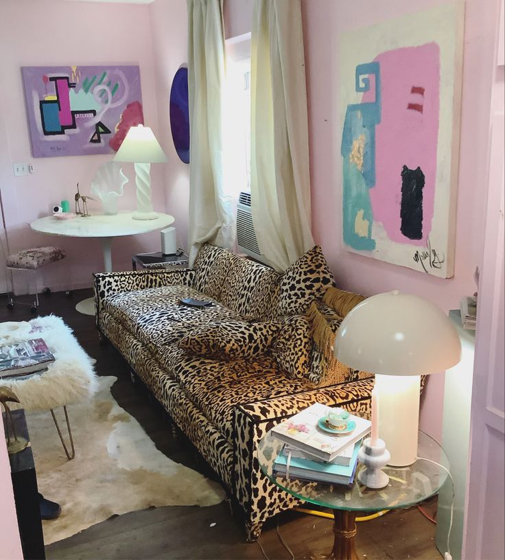 a living room with pink walls and leopard print furniture in the corner, including a couch