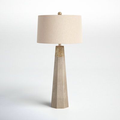 a table lamp with a beige shade on it's base and a white background