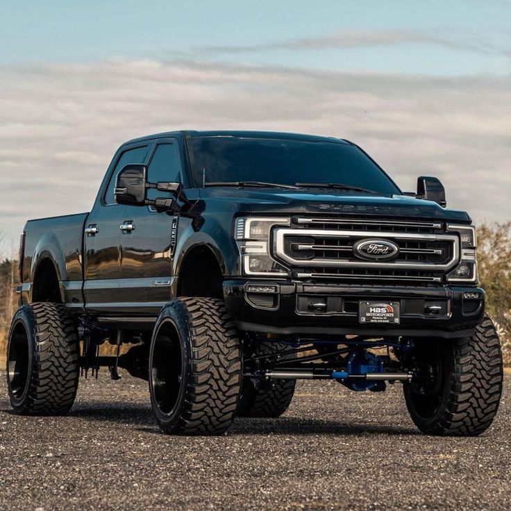 a large black truck parked on top of a gravel road