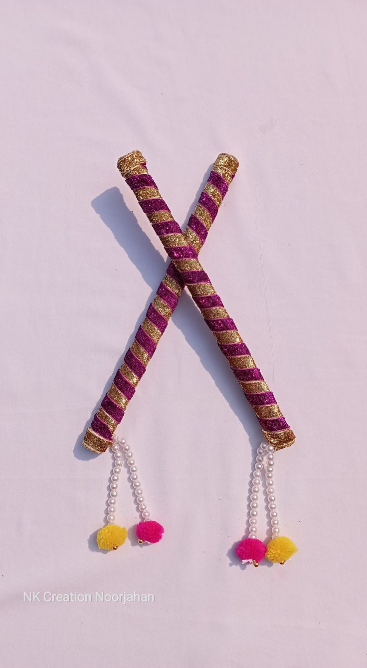 two sticks with tassels attached to them on a white surface