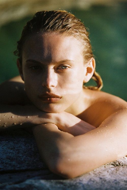 a beautiful young woman laying on top of a rock