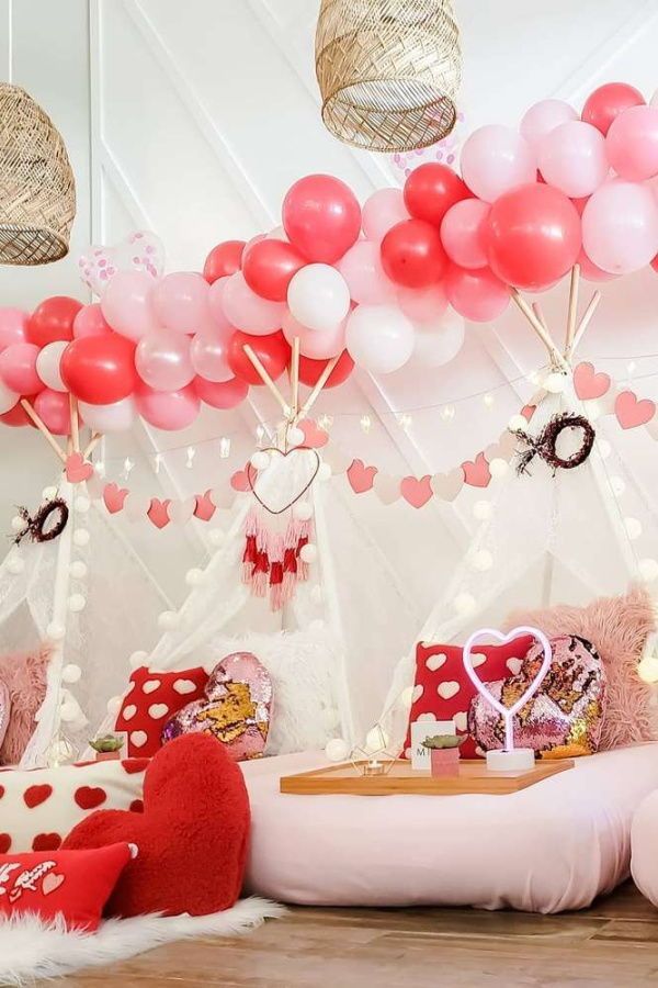 a room filled with lots of pink and red balloons