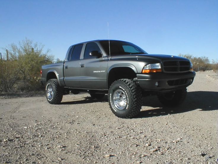 a silver truck parked on top of a dirt road