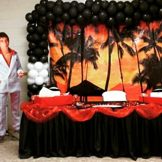 a man standing next to a table with black and white balloons