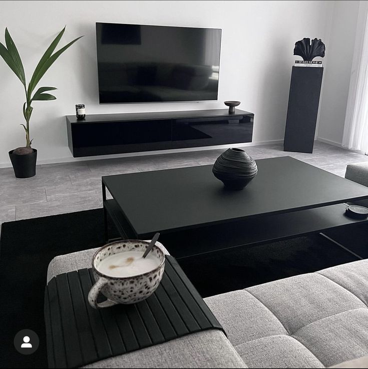 a modern living room with black and white furniture, large flat screen tv on the wall