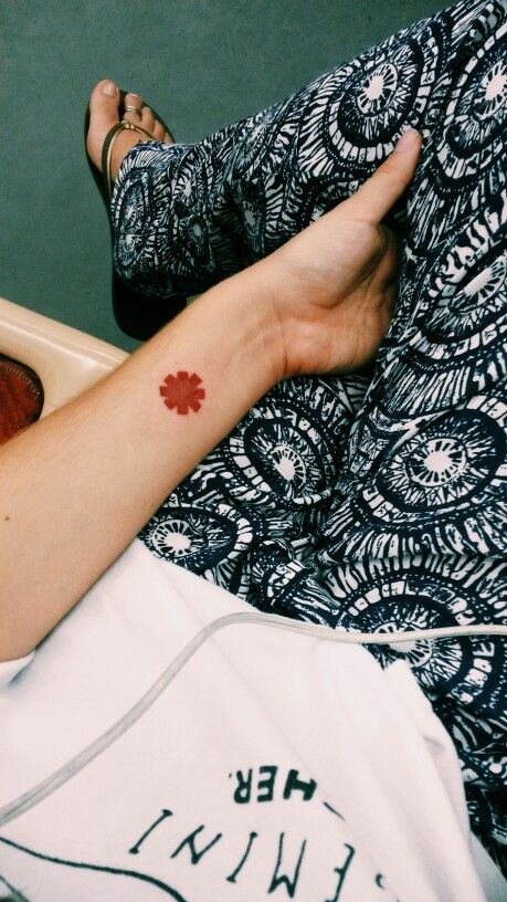 a woman with a red flower tattoo on her left arm and right leg, sitting in a chair