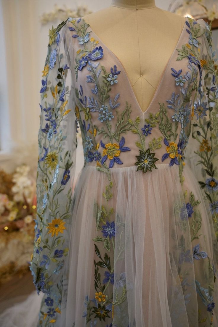 a dress with flowers on it sitting on a mannequin