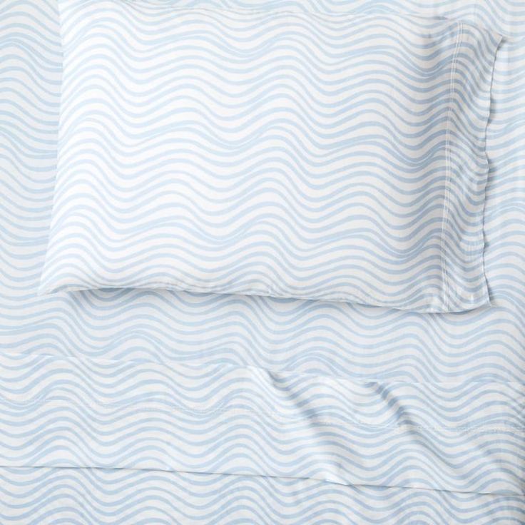 a bed with blue waves on the sheets and pillowcases in front of it