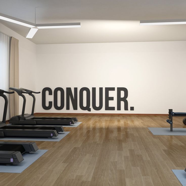 there is a gym with treadmills and exercise equipment in it, as well as a sign that says conquer