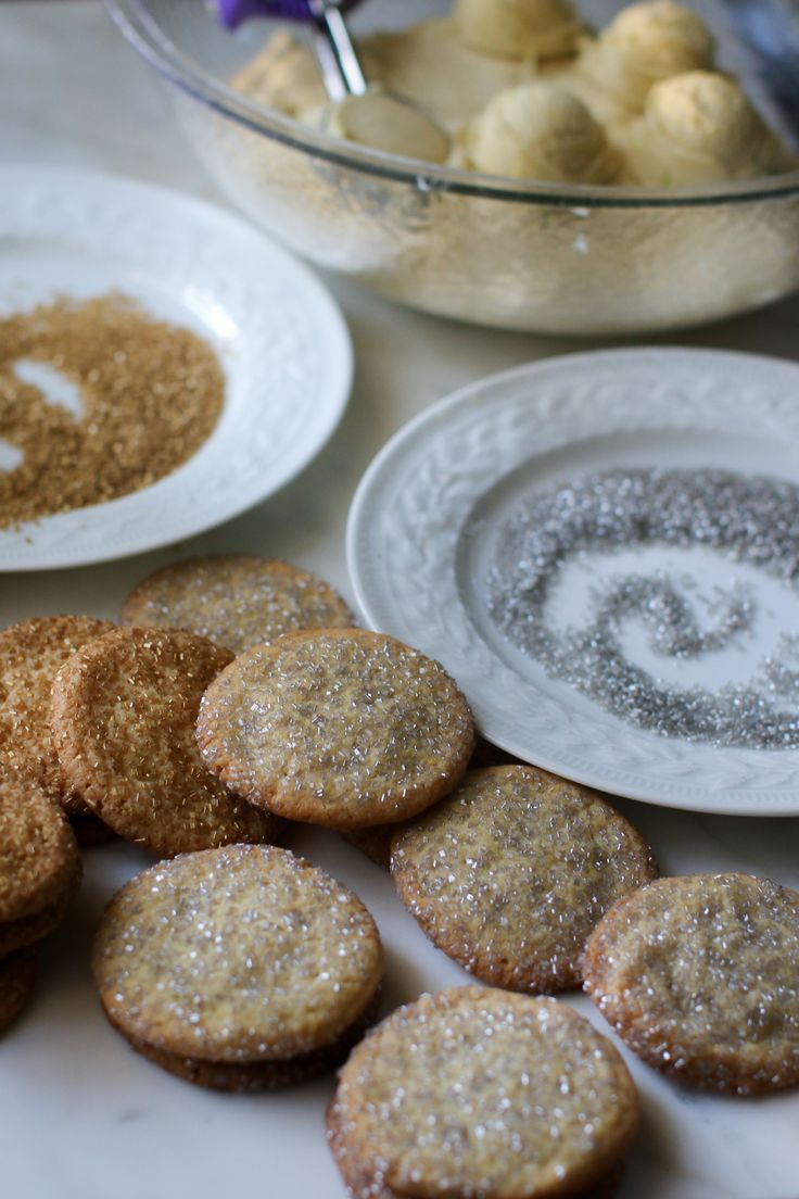 some cookies are sitting on a table next to bowls and plates with desserts in them