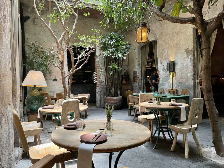 an outdoor dining area with tables, chairs and potted trees in the middle of it