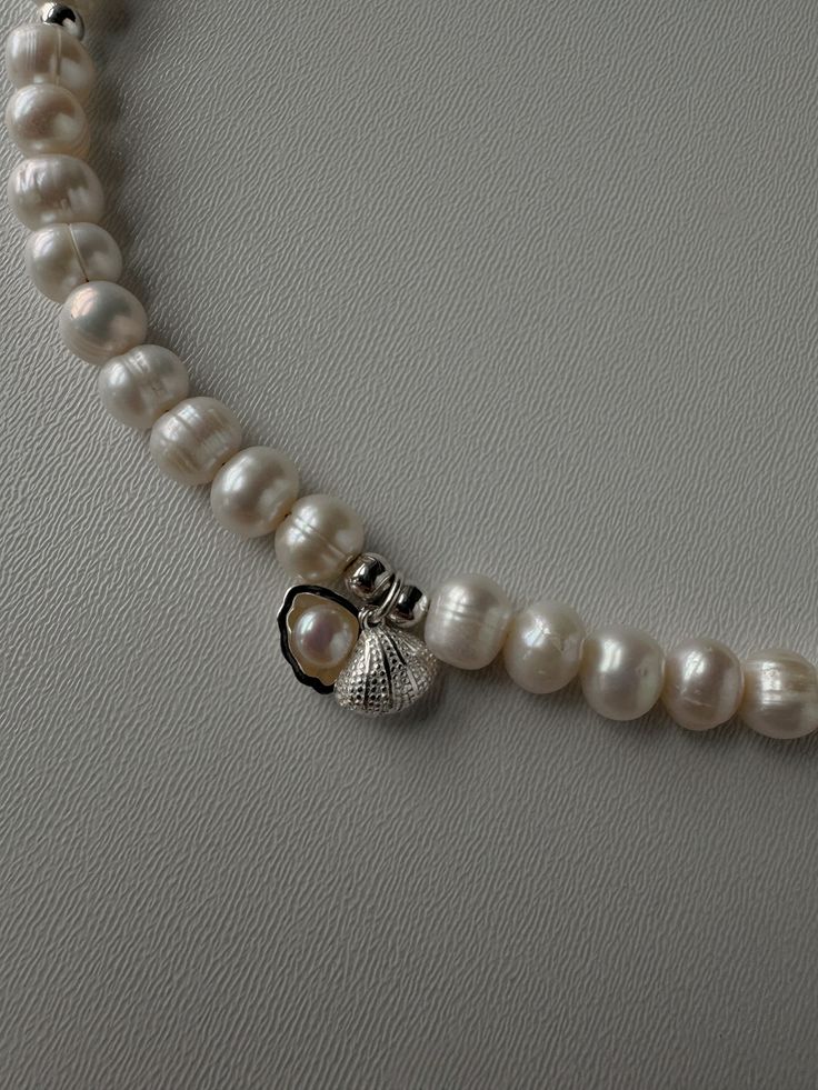 This delicate pearl necklace with a sea shell pendant is an ideal choice for women who appreciate elegance and natural beauty. Its classic design makes the jewelry versatile: it will emphasize the elegance of a bride's wedding dress or add charm to an evening gown at a special event. The necklace will also be an exquisite addition to a business style or a romantic date look. This accessory can be presented for special occasions such as a birthday, anniversary, wedding or anniversary. It is a wonderful gift for a loved one, mother, sister or friend that will express your love, gratitude and care. A natural pearl necklace with a sea shell pendant is not just a piece of jewelry, but a symbol of femininity and refined taste. material - pearls, sterling silver Length - 40 cm (15.7 inches) + 6 c Elegant Shell-shaped Pearl Drop Necklace, Elegant Pearl Charm Shell Necklace, Elegant Pearl Necklace With Shell And Pearl Charm, Elegant Shell-shaped Necklace With Pearl Charm, Elegant Shell Pearl Necklace With Pearl Charm, Shell-shaped Pearl Necklace With Pearl Pendant, Elegant Shell Pearl Chain Necklace, Elegant Pearl Chain Necklace Made Of Shell, Silver Pearl Shell Necklace As A Gift