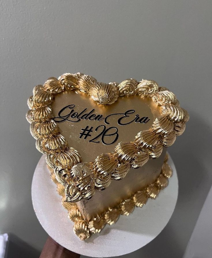 a golden heart shaped cake on top of a white stand