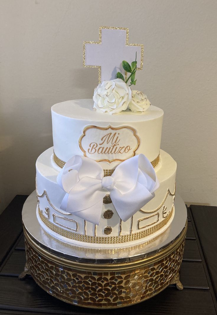 a three tiered cake with white flowers on top and gold trim around the edges